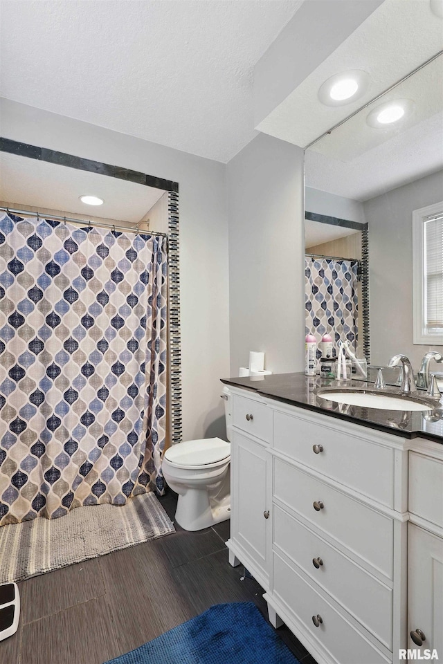 bathroom with vanity, toilet, a shower with shower curtain, recessed lighting, and wood finished floors