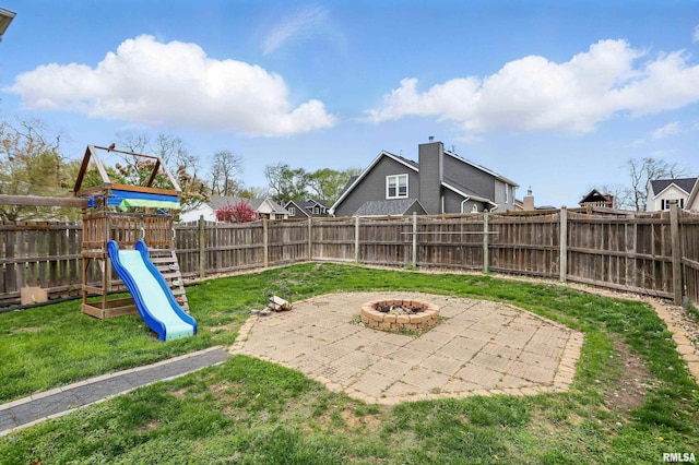 view of yard featuring a fenced backyard, a fire pit, a playground, and a patio area
