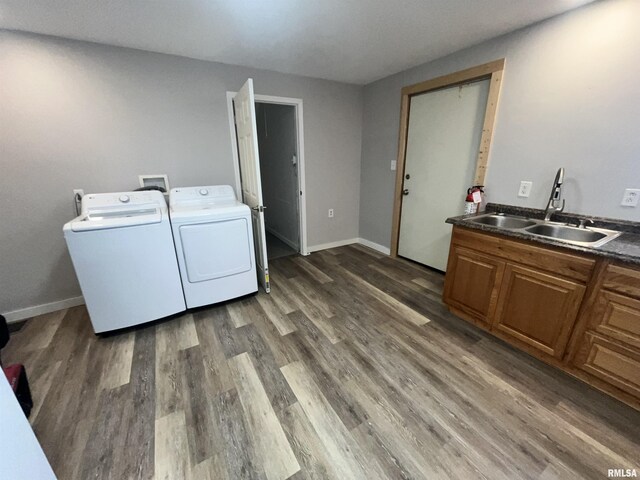 laundry area with laundry area, wood finished floors, baseboards, washer and clothes dryer, and a sink
