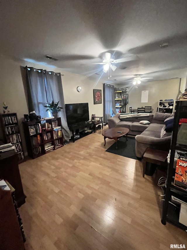 living area with visible vents, ceiling fan, and wood finished floors