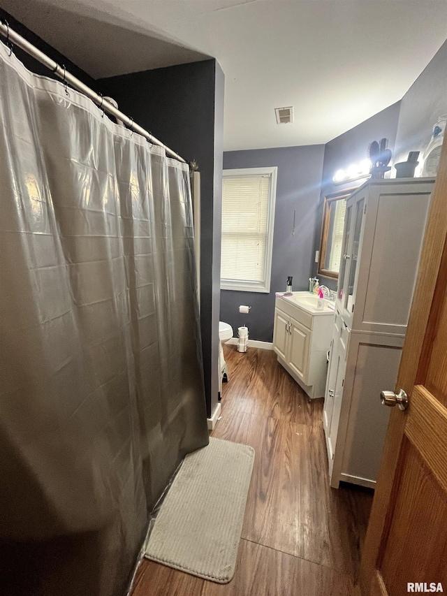 bathroom with visible vents, wood finished floors, vanity, baseboards, and toilet