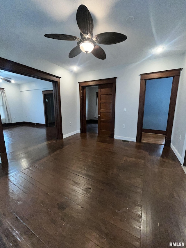 unfurnished room featuring wood-type flooring, a ceiling fan, baseboards, and visible vents