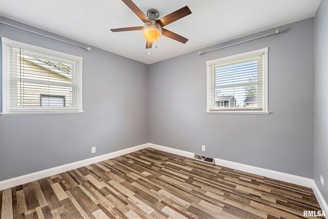 spare room featuring a healthy amount of sunlight, baseboards, wood finished floors, and visible vents