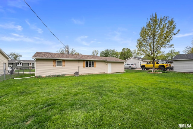 rear view of house with fence and a lawn