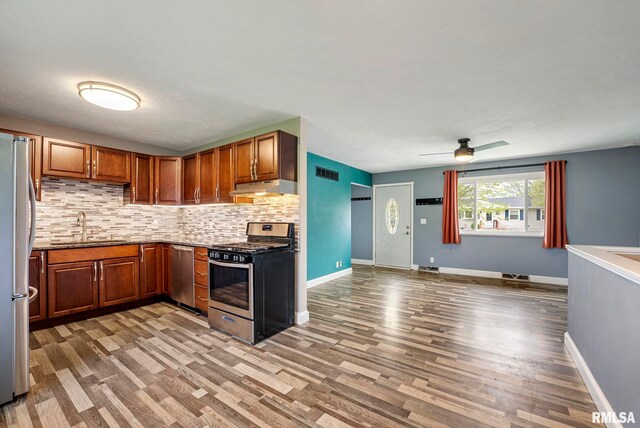 kitchen featuring a sink, stainless steel appliances, wood finished floors, under cabinet range hood, and visible vents