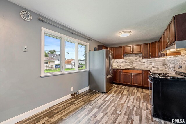 kitchen featuring backsplash, visible vents, light wood finished floors, under cabinet range hood, and stainless steel appliances