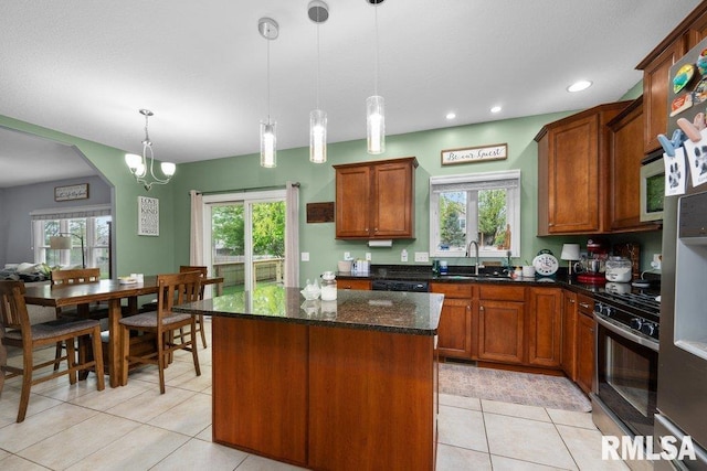 kitchen featuring plenty of natural light, a center island, a sink, light tile patterned floors, and stainless steel range with gas cooktop
