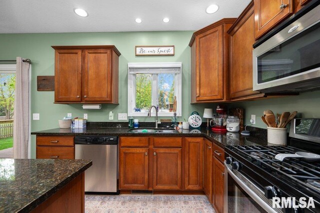 kitchen with recessed lighting, a sink, dark stone countertops, and appliances with stainless steel finishes