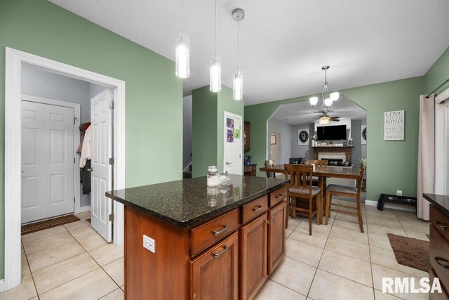 kitchen with brown cabinets, light tile patterned flooring, ceiling fan, and hanging light fixtures