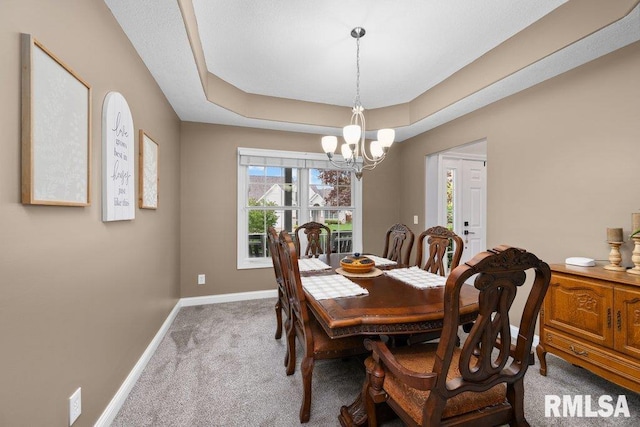 dining space featuring baseboards, carpet flooring, a raised ceiling, and a chandelier