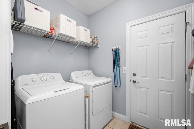 clothes washing area with baseboards, laundry area, washing machine and dryer, and light tile patterned floors