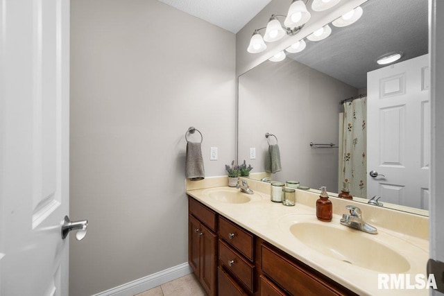 bathroom with double vanity, a sink, baseboards, and tile patterned floors