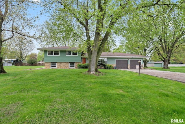 split level home featuring a garage, a front lawn, fence, and driveway
