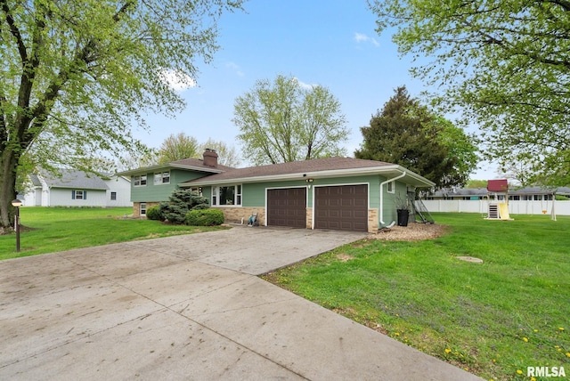 split level home with a front lawn, fence, a chimney, an attached garage, and driveway