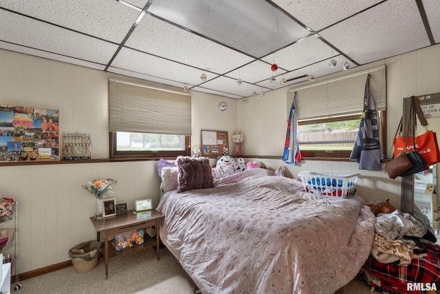 bedroom with carpet floors, a paneled ceiling, and a decorative wall