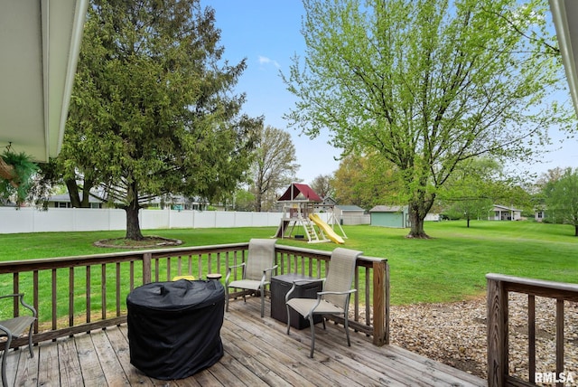 wooden terrace featuring a playground, fence, and a yard