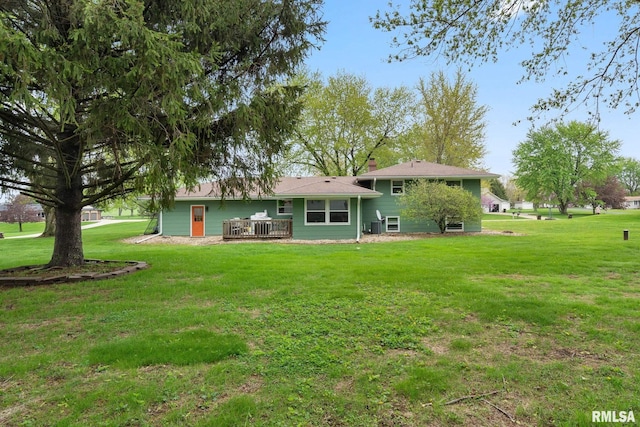 rear view of property with a wooden deck and a yard