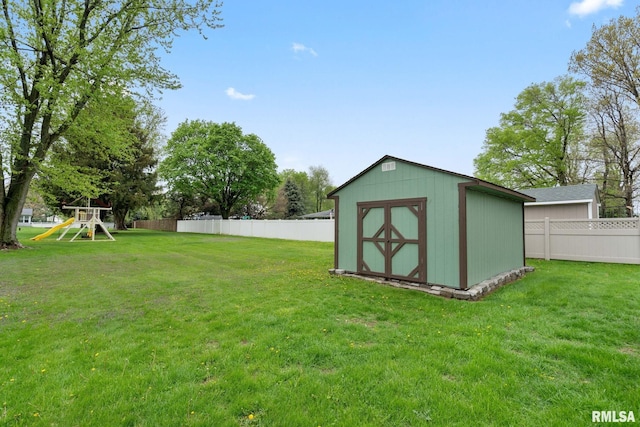 view of yard with a playground, an outbuilding, a fenced backyard, and a shed
