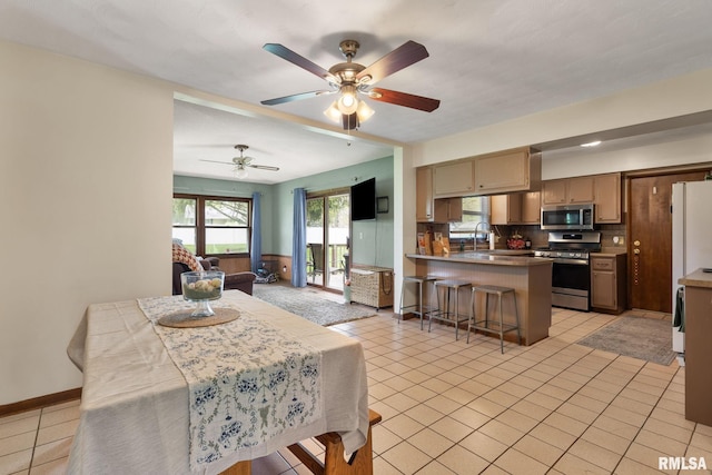 dining space featuring light tile patterned floors, baseboards, and a ceiling fan