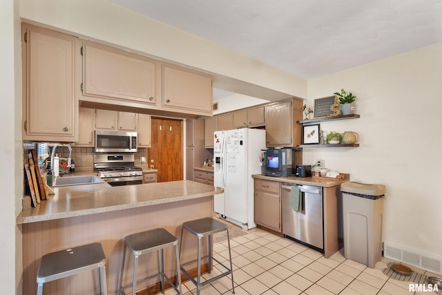 kitchen featuring visible vents, a peninsula, light countertops, a sink, and stainless steel appliances