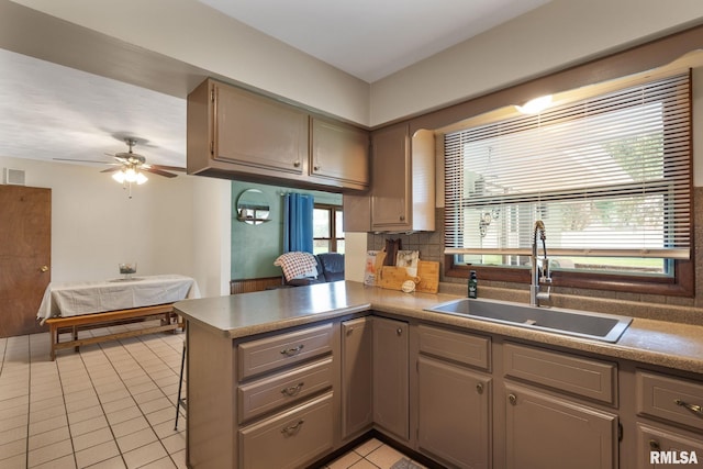 kitchen with light tile patterned flooring, a healthy amount of sunlight, a sink, and a peninsula