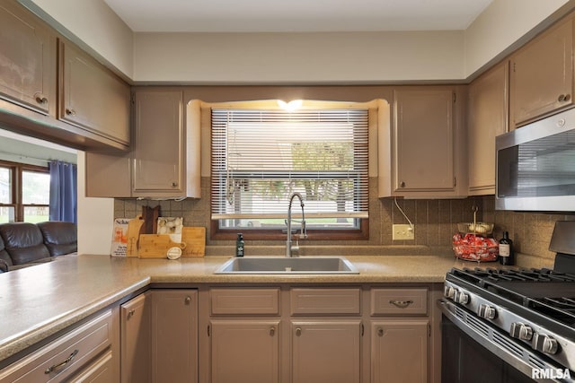 kitchen featuring a sink, backsplash, stainless steel appliances, and a wealth of natural light