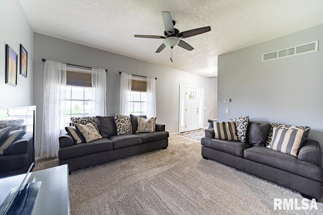 carpeted living room featuring ceiling fan, a textured ceiling, and visible vents