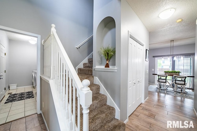 staircase featuring a textured ceiling and baseboards
