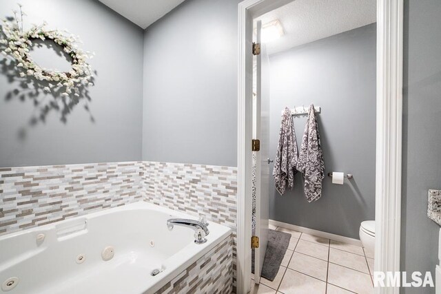 bathroom featuring tile patterned floors, toilet, and a tub with jets