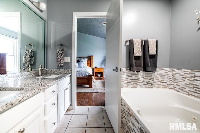 ensuite bathroom featuring a sink, ensuite bath, double vanity, tile patterned floors, and a whirlpool tub