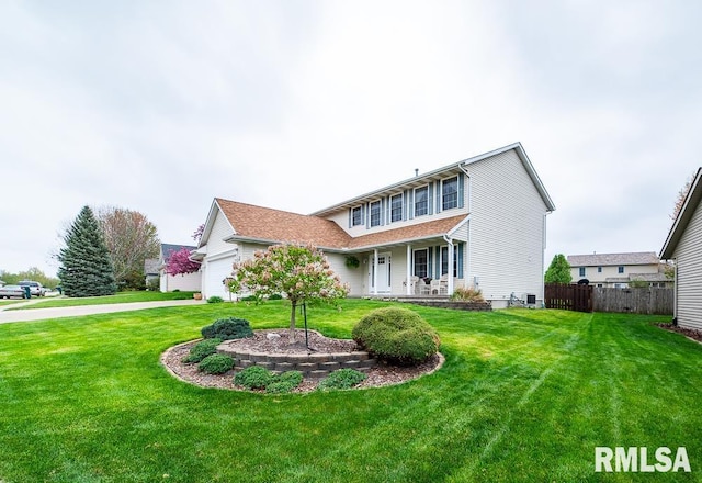 traditional-style home with fence, covered porch, a garage, and a front yard