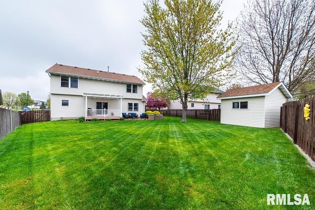 back of property featuring a lawn, an outdoor structure, a fenced backyard, and a deck
