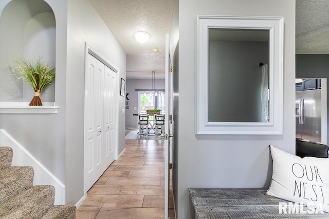 hall with stairs, a textured ceiling, and wood finished floors