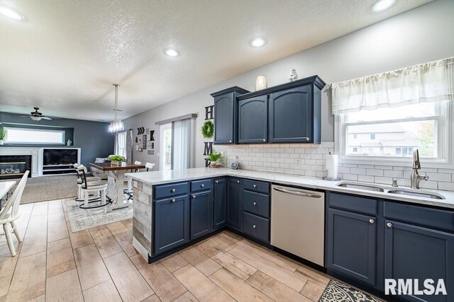 kitchen featuring a sink, light countertops, a ceiling fan, a peninsula, and stainless steel dishwasher