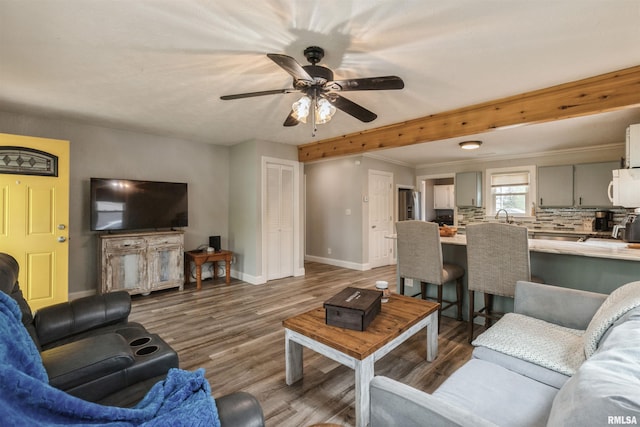 living room featuring a ceiling fan, baseboards, and wood finished floors