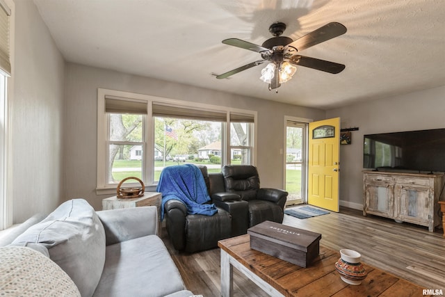 living area featuring baseboards, ceiling fan, and wood finished floors