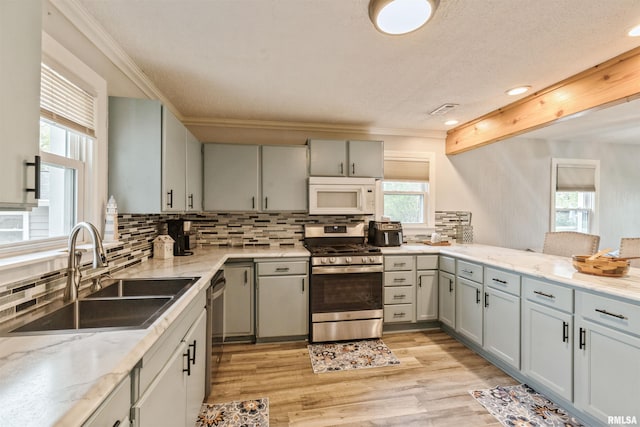 kitchen with backsplash, crown molding, appliances with stainless steel finishes, and a sink