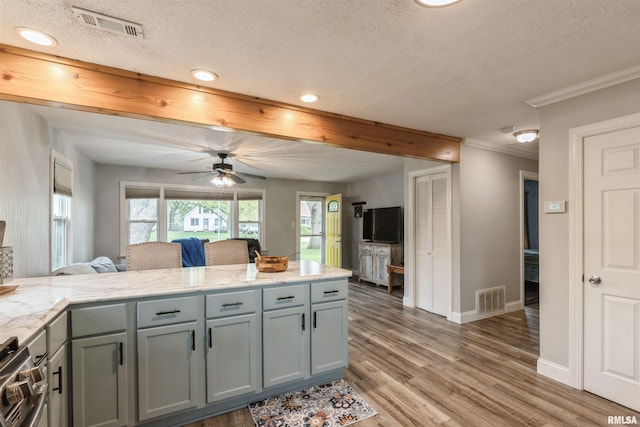 kitchen with light wood-style flooring, a peninsula, a textured ceiling, and visible vents