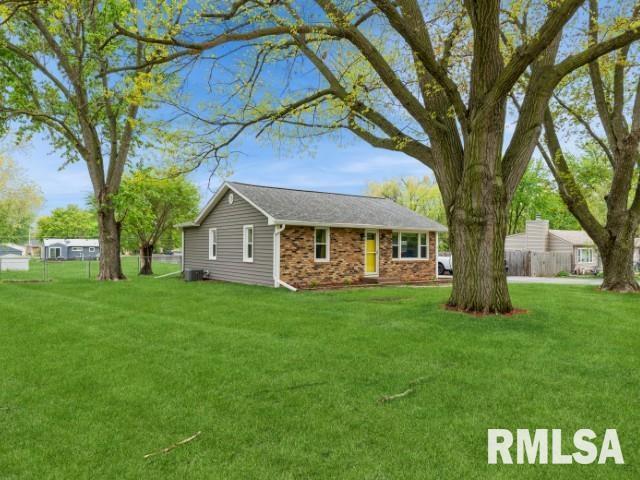 view of front of home with brick siding, fence, a front yard, and cooling unit