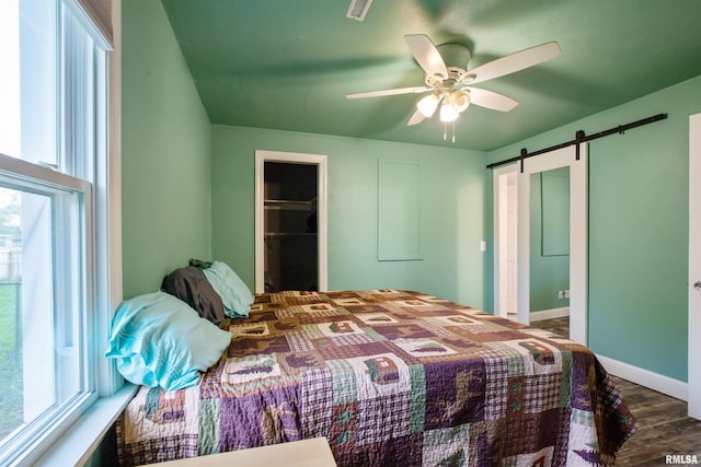 bedroom with visible vents, a closet, wood finished floors, a walk in closet, and a barn door