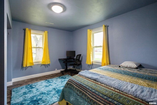 bedroom featuring baseboards, multiple windows, and wood finished floors