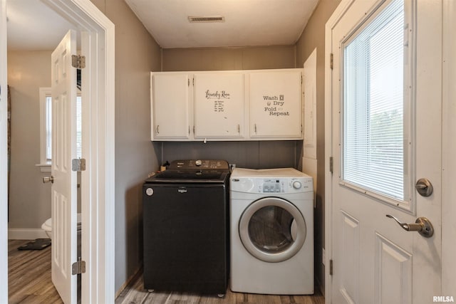 clothes washing area with visible vents, baseboards, washing machine and clothes dryer, cabinet space, and light wood finished floors