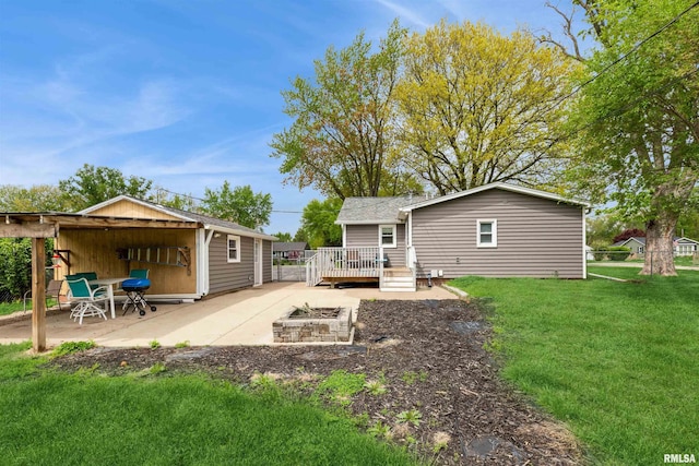 back of property with a yard, a patio, a fire pit, and a wooden deck