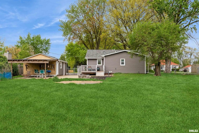 rear view of property featuring a yard, a deck, fence, and a patio area
