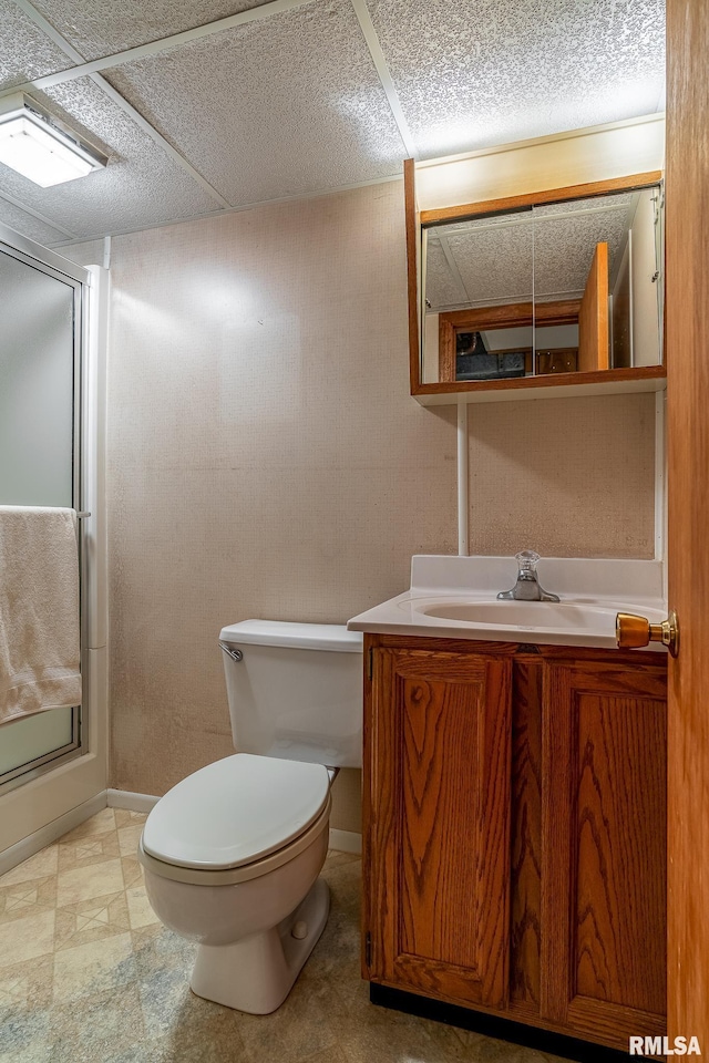bathroom with vanity, toilet, tile patterned floors, baseboards, and a shower with door