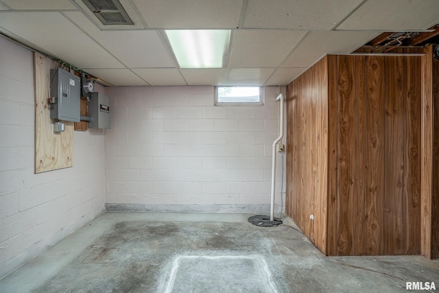 basement with visible vents, electric panel, and concrete block wall