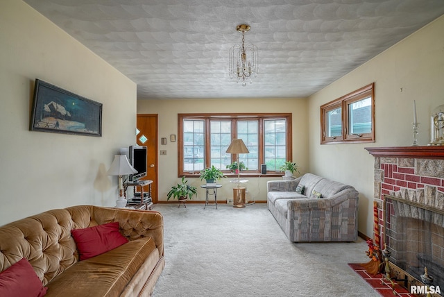 living room with baseboards, carpet flooring, a notable chandelier, and a fireplace