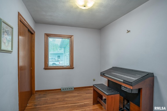 misc room featuring baseboards, wood finished floors, and visible vents