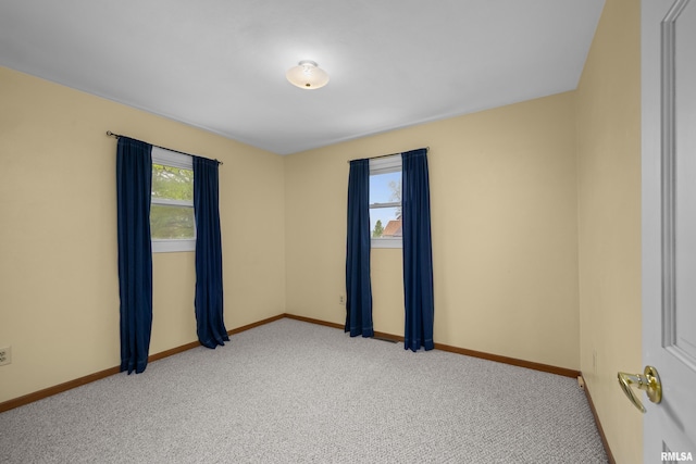 empty room featuring baseboards and light carpet