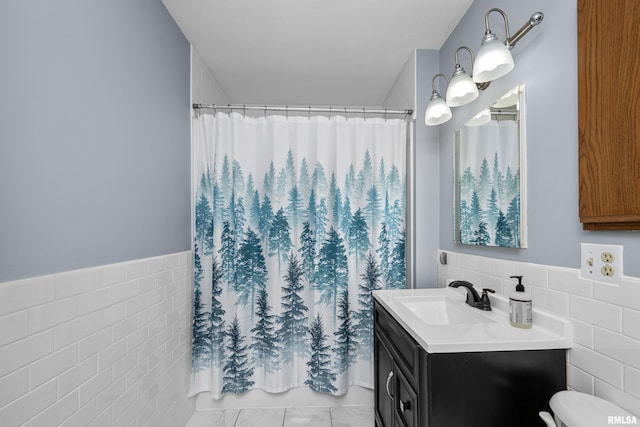 full bathroom featuring vanity, wainscoting, a shower with curtain, and tile walls